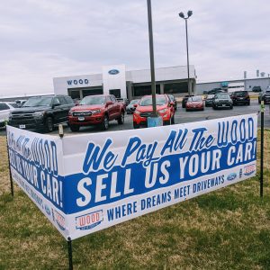 Full Colored Printed Banners outside of Wood Ford in Carthage, MO. Banners that read "We Pay All The Wood. Sell Us Your Car. Where Dreams Meet Driveways"