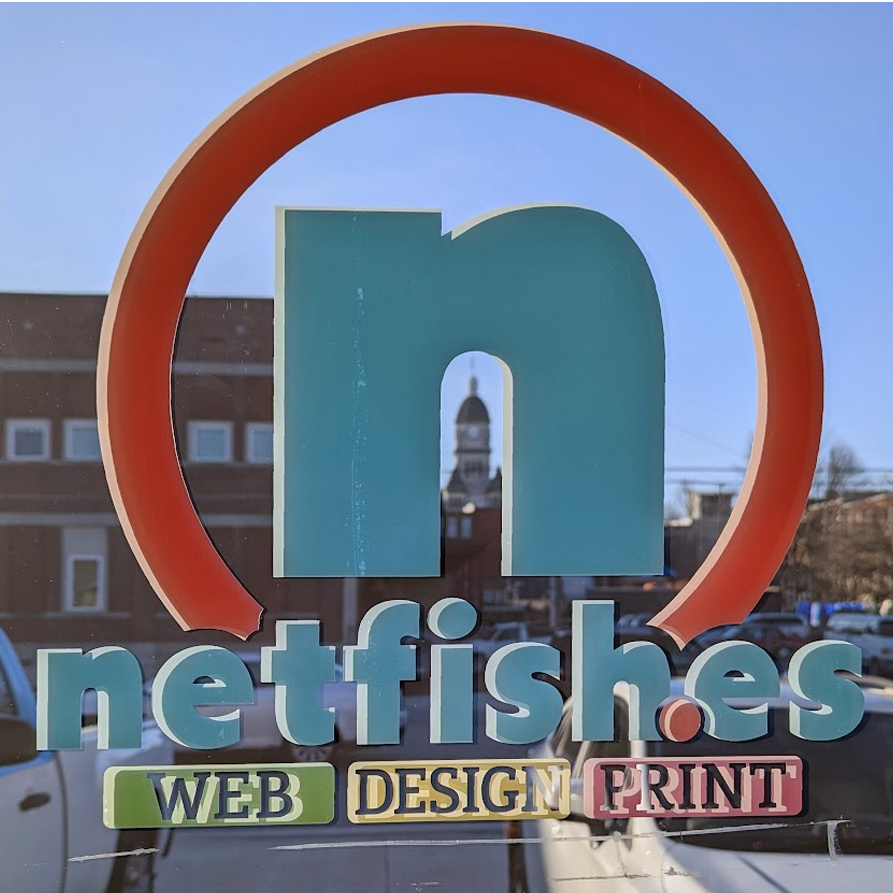 A view of the Carthage Courthouse square through the office door's newly printed & cut vinyl lettering that says "netfishes web, design, print"
