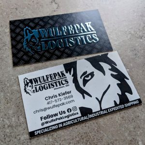 raised silver foil and matte front with Wulfepak Logistics. The back is black and white with a wolf sillouette and contact information.