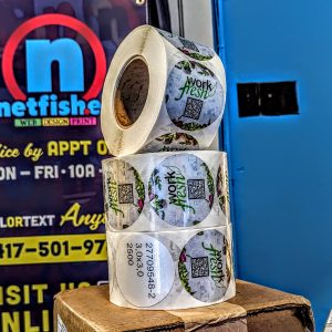 Rolls of 3 inch round stickers with work fresh on them as well as qr code.